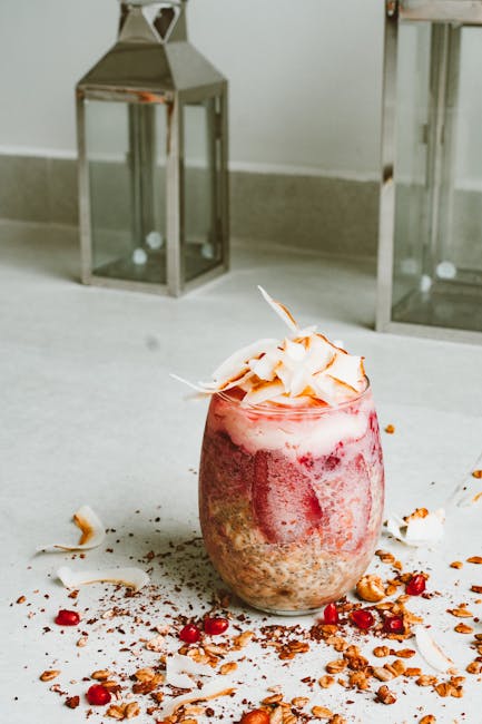 Refreshing strawberry and pomegranate smoothie topped with coconut flakes on a white surface.