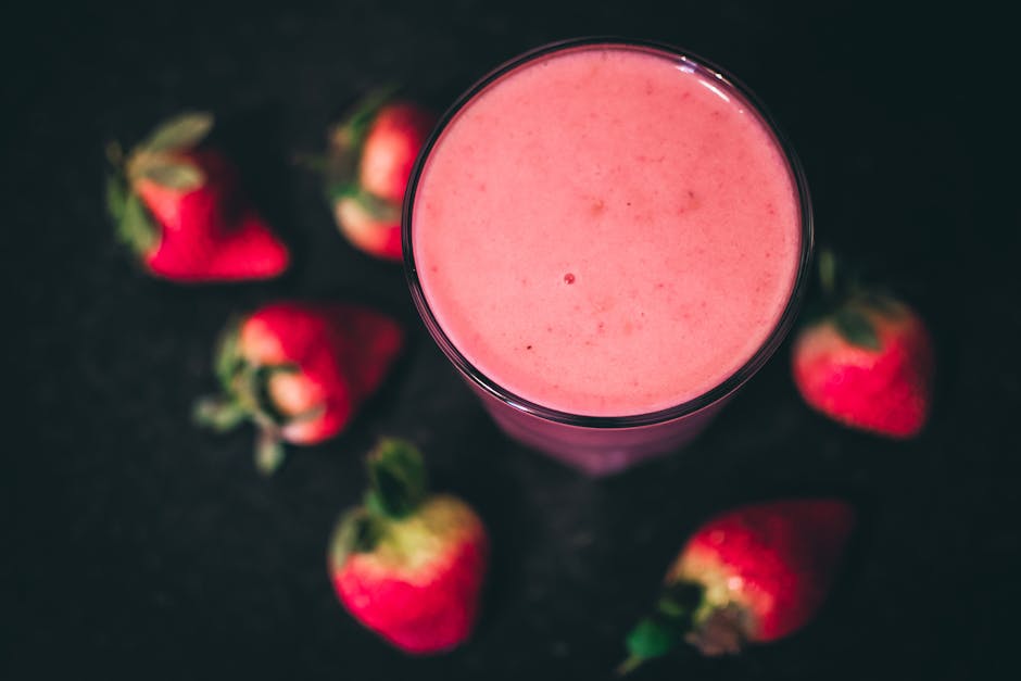Top view of a refreshing strawberry smoothie surrounded by ripe strawberries.